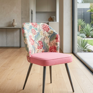 Premium metal dining chair with pink velvet cushion seat and floral printed backrest facing front in a modern dining room.