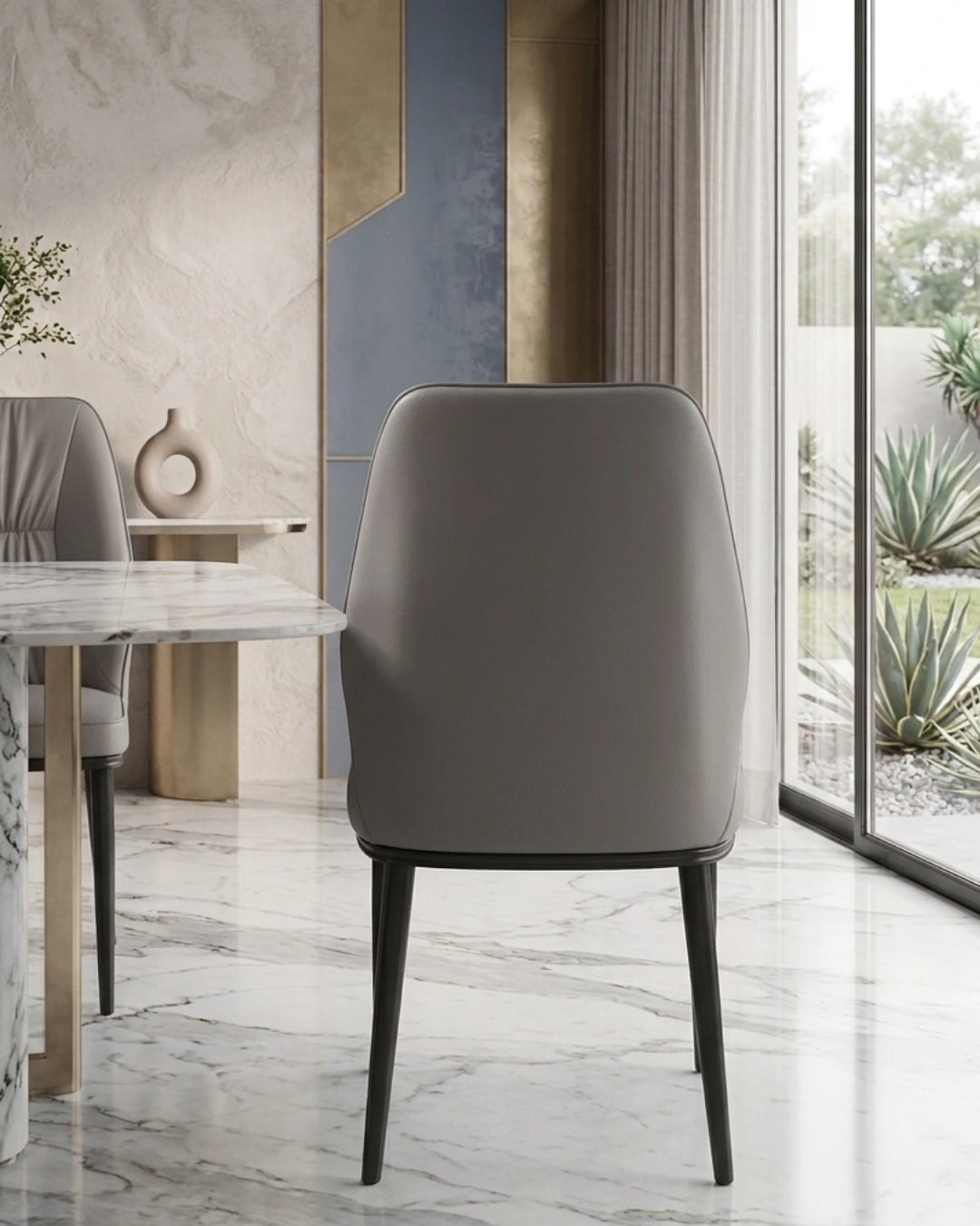 Premium taupe grey leatherette dining chair with pleated backrest design and sleek black metal legs viewed from the side profile in a modern home kitchen setup.